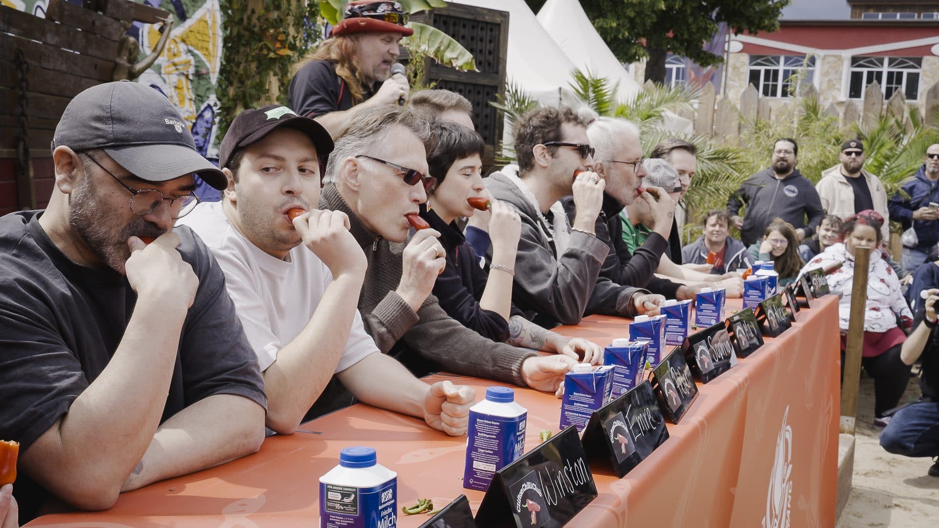 Tasters working down a long bench at Berlin Chili Fest, sampling hot sauces at Berliner Berg Brauerei.